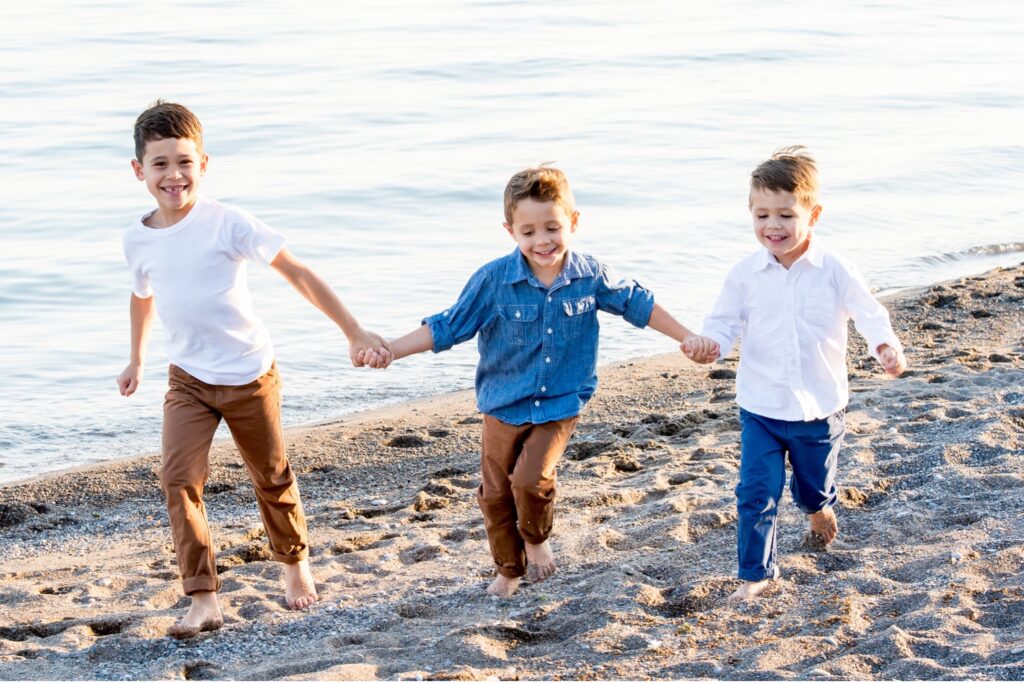 three boys running on the beach